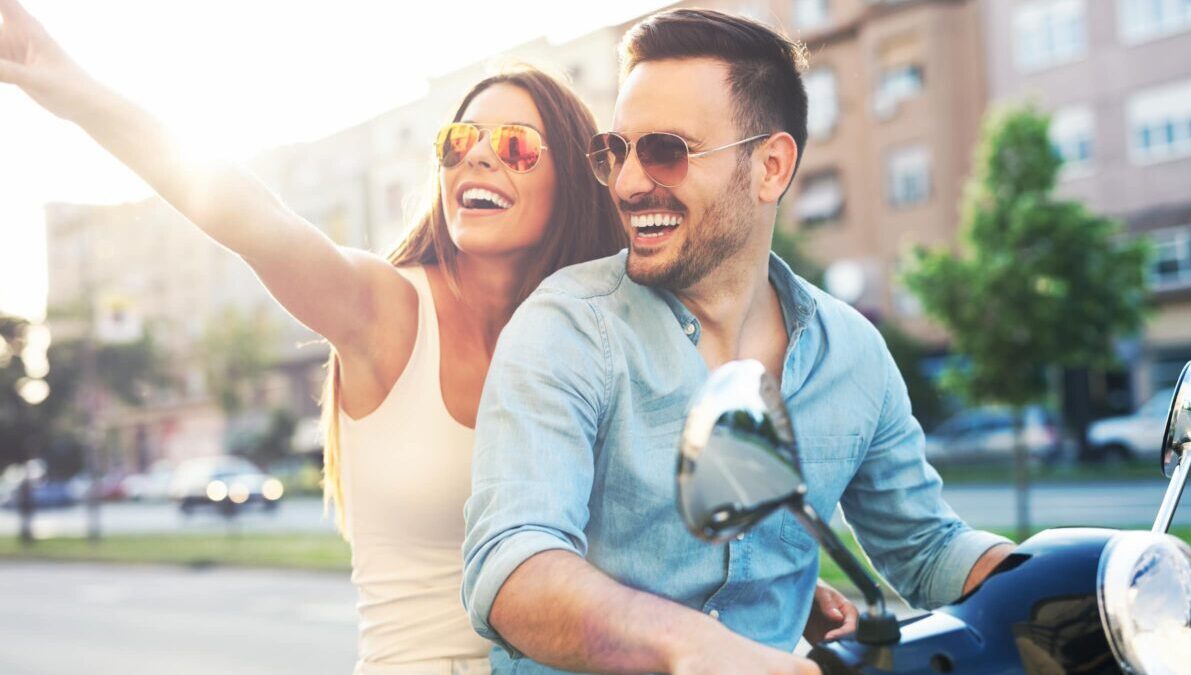 Young happy couple riding moped