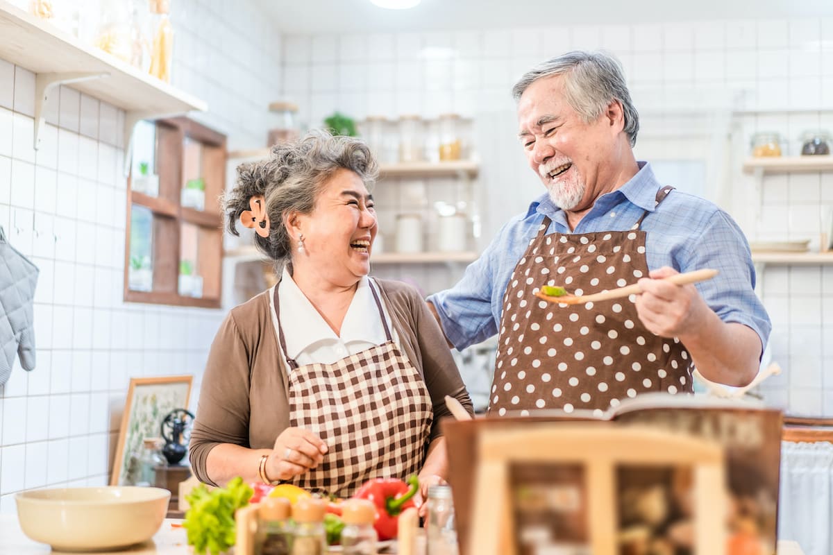 happy senior couple cooking at home